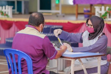 Muadzam Şah, Malezya - 25 Ocak 2022: Öğretmen salonda tükürük örneğiyle Covid-19 hızlı testi yaptı.