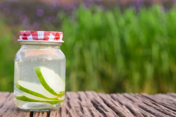 Detox water with lime in jar against rustic wood
