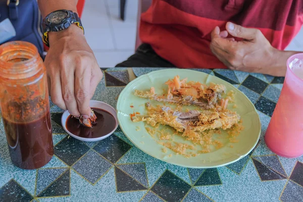 一个人正在享受吃油炸鱼或 Ikan Celup Tepung 的乐趣 这在Terengganu是最有名的 用面粉煎的鲜鱼成为旅游胜地 — 图库照片