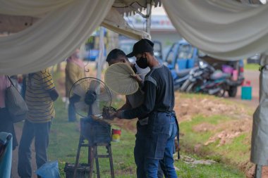 Segamat, Malezya - 2 Nisan 2022: Müslüman erkek satıcılar Kuantan 'daki kutsal Ramazan ayında yol kenarındaki tezgahlardan helal yiyecekler pişirip satıyorlar.