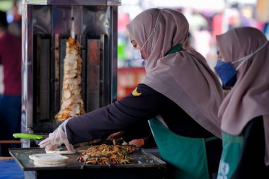 Segamat, Malezya - 2 Nisan 2022: Müslüman kadın satıcılar Kuantan 'daki kutsal Ramazan ayında yol kenarındaki tezgahlardan helal yiyecekler pişirip satıyorlar.