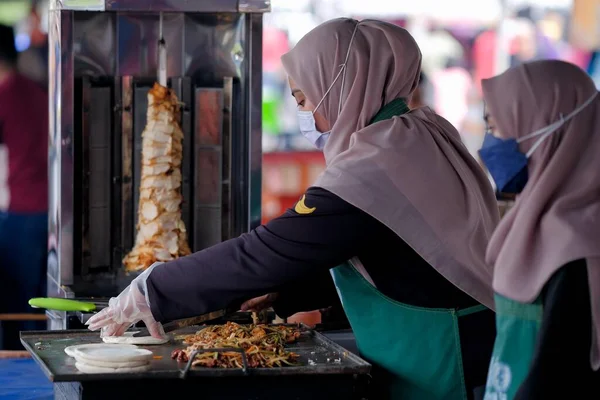 Segamat, Malaysia- April 2nd, 2022 : Muslim female vendors cooking and  selling halal foods from roadside stall  in holy month of Ramadan at Kuantan.