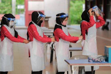 Muadzam Şah, Malezya - 7 Nisan 2022: Öğrenci kayıt gününde PPE takım elbise giyen ve yüz maskesi takan öğrenci.