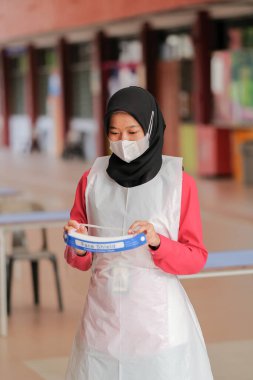 Muadzam Shah, Malaysia - April 7th, 2022 :  Student wearing PPE suit and face shield  during  student enrolment day.