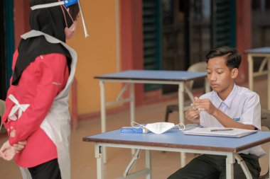 Muadzam Shah, Malaysia - April 7th, 2022 : New students made a quick Covid-19 test by placing saliva and fluid buffer observations during student enrolment day.