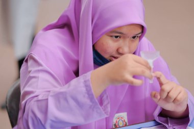 Muadzam Shah, Malaysia - April 7th, 2022 : Lateral-Flow-Test covid rapid home-use test kit for saliva - step 2 - spit with mouth through funnel in plastic tube to collect sample.