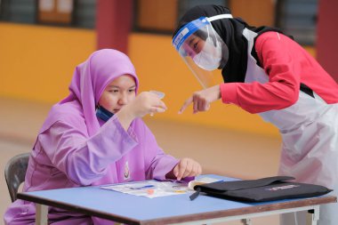 Muadzam Shah, Malaysia - April 7th, 2022 : Lateral-Flow-Test covid rapid home-use test kit for saliva - step 2 - spit with mouth through funnel in plastic tube to collect sample.