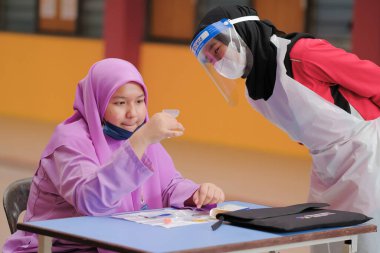 Muadzam Shah, Malaysia - April 7th, 2022 : Lateral-Flow-Test covid rapid home-use test kit for saliva - step 2 - spit with mouth through funnel in plastic tube to collect sample.