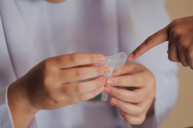 Muadzam Shah, Malaysia - April 7th, 2022 : Lateral-Flow-Test covid rapid home-use test kit for saliva - step 2 - spit with mouth through funnel in plastic tube to collect sample.
