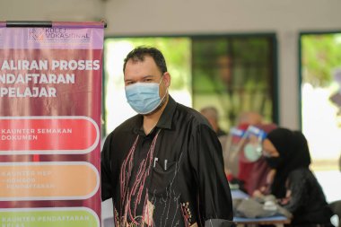 Muadzam Shah, Malaysia - April 7th, 2022 :  Happy muslim staff with protective mask during  student enrolment day.