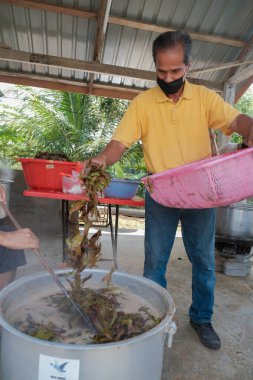 Muadzan Şah, Malezya - 16 Nisan 2022: Bubur Lambuk adlı lezzetli geleneksel lapayı pişirmeye, hazırlamaya ve dağıtmaya yardım eden gönüllüler.