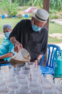 Muadzan Şah, Malezya - 16 Nisan 2022: Bubur Lambuk adlı lezzetli geleneksel lapayı pişirmeye, hazırlamaya ve dağıtmaya yardım eden gönüllüler.