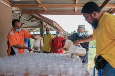Muadzan Şah, Malezya - 16 Nisan 2022: Bubur Lambuk adlı lezzetli geleneksel lapayı pişirmeye, hazırlamaya ve dağıtmaya yardım eden gönüllüler.