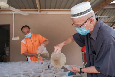 Muadzan Şah, Malezya - 16 Nisan 2022: Bubur Lambuk adlı lezzetli geleneksel lapayı pişirmeye, hazırlamaya ve dağıtmaya yardım eden gönüllüler.