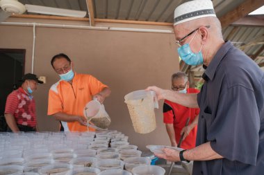 Muadzam Şah, Malezya - 16 Nisan 2022: Bubur Lambuk adlı lezzetli geleneksel lapayı pişirmeye, hazırlamaya ve dağıtmaya yardım eden gönüllüler.