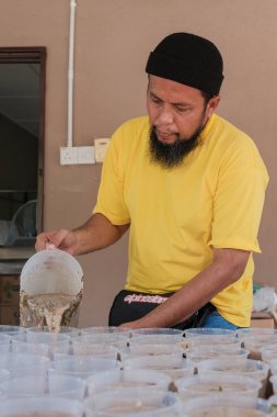 Muadzam Şah, Malezya - 16 Nisan 2022: Bubur Lambuk adlı lezzetli geleneksel lapayı pişirmeye, hazırlamaya ve dağıtmaya yardım eden gönüllüler.