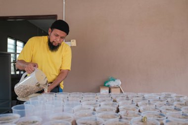 Muadzam Şah, Malezya - 16 Nisan 2022: Bubur Lambuk adlı lezzetli geleneksel lapayı pişirmeye, hazırlamaya ve dağıtmaya yardım eden gönüllüler.