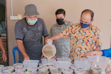 Muadzam Şah, Malezya - 16 Nisan 2022: Bubur Lambuk adlı lezzetli geleneksel lapayı pişirmeye, hazırlamaya ve dağıtmaya yardım eden gönüllüler.