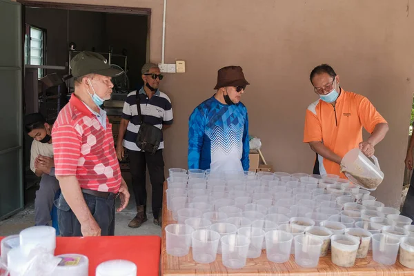 Muadzan Şah, Malezya - 16 Nisan 2022: Bubur Lambuk adlı lezzetli geleneksel lapayı pişirmeye, hazırlamaya ve dağıtmaya yardım eden gönüllüler.