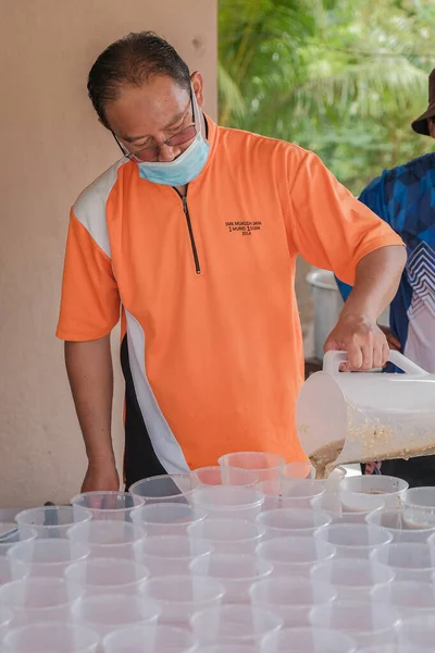 Muadzan Şah, Malezya - 16 Nisan 2022: Bubur Lambuk adlı lezzetli geleneksel lapayı pişirmeye, hazırlamaya ve dağıtmaya yardım eden gönüllüler.