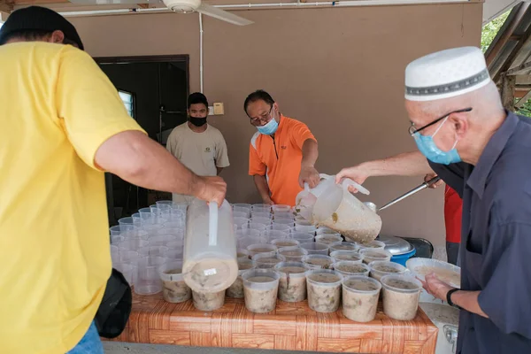 Muadzam Şah, Malezya - 16 Nisan 2022: Bubur Lambuk adlı lezzetli geleneksel lapayı pişirmeye, hazırlamaya ve dağıtmaya yardım eden gönüllüler.