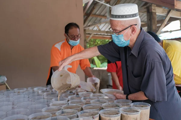 Muadzam Şah, Malezya - 16 Nisan 2022: Bubur Lambuk adlı lezzetli geleneksel lapayı pişirmeye, hazırlamaya ve dağıtmaya yardım eden gönüllüler.
