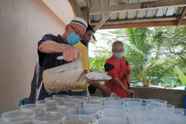 Muadzam Şah, Malezya - 16 Nisan 2022: Bubur Lambuk adlı lezzetli geleneksel lapayı pişirmeye, hazırlamaya ve dağıtmaya yardım eden gönüllüler.
