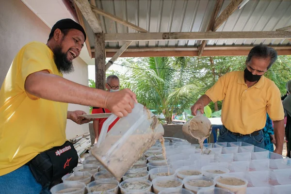 Muadzam Şah, Malezya - 16 Nisan 2022: Bubur Lambuk adlı lezzetli geleneksel lapayı pişirmeye, hazırlamaya ve dağıtmaya yardım eden gönüllüler.