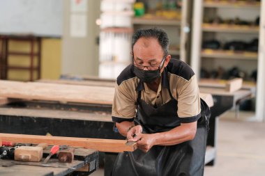 Marangoz atölyede ahşap işçiliği üzerine çalışarak inşaat malzemesi veya ahşap mobilya üretiyor.