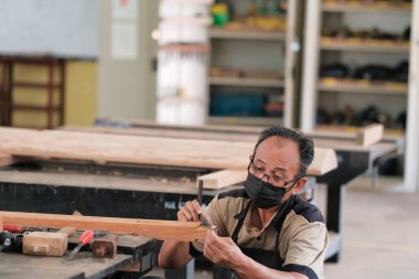 Marangoz atölyede ahşap işçiliği üzerine çalışarak inşaat malzemesi veya ahşap mobilya üretiyor.