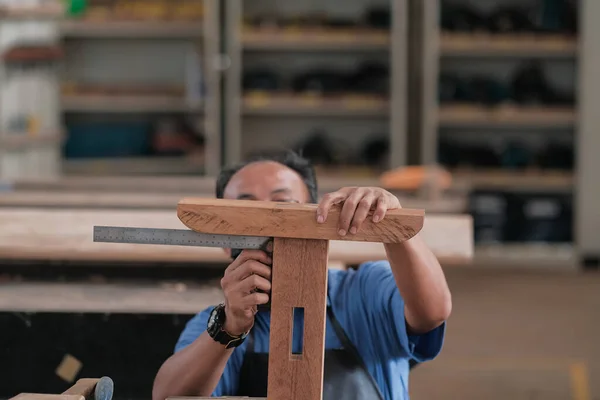 Atölyede elektrikli zımpara makinesi kullanan yaşlı bir marangoz ya da marangoz. Ahşap mobilya üretiminde doğrama işi. Küçük İş Konsepti