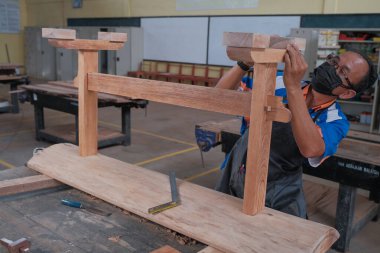 Senior male woodworker making console table  in workshop. Joinery work on the production  of wooden furniture. Small Business Concept