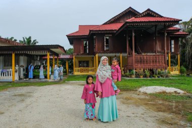 Batu Pahat, Malezya - 3 Mayıs 2022: Geleneksel kıyafetler içinde mutlu Malay ailesi ve Hari Raya sırasındaki geleneksel Malay evi. Malezya aile yaşam tarzı evde. Mutluluk kavramı.
