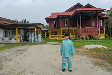 Batu Pahat, Malezya - 3 Mayıs 2022: Geleneksel kıyafetler içinde mutlu Malay ailesi ve Hari Raya sırasındaki geleneksel Malay evi. Malezya aile yaşam tarzı evde. Mutluluk kavramı.