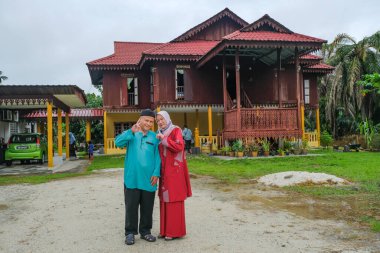 Batu Pahat, Malezya - 3 Mayıs 2022: Geleneksel kıyafetler içinde mutlu Malay ailesi ve Hari Raya sırasındaki geleneksel Malay evi. Malezya aile yaşam tarzı evde. Mutluluk kavramı.