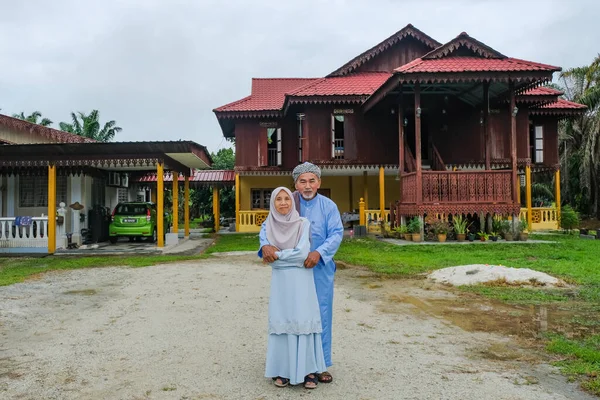 Batu Pahat, Malaysia - May 3rd, 2022 :  Happy Malay family in traditional clothing and traditional Malay house during Hari Raya. Malaysian family lifestyle at home. Happiness concept.