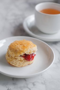 Çörekli çay, pıhtılaşmış krema, reçel, beyaz masada çilek.