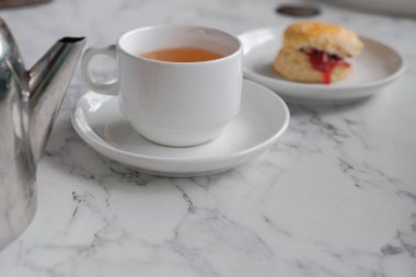 Çörekli çay, pıhtılaşmış krema, reçel, beyaz masada çilek.