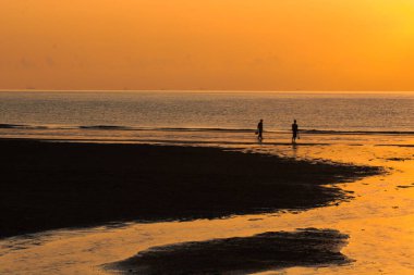 Gün doğumuna karşı yürüyen çift silueti.