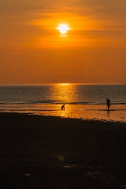 Gün doğumuna karşı yürüyen çift silueti.