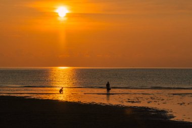Gün doğumuna karşı yürüyen çift silueti.