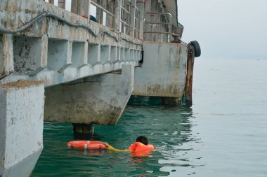Tioman, Malezya - 20 Nisan 2022: İnşaat işçisi beton bir iskeleyi onarmak için deniz suyunun üzerinde yapı iskelesi kuruyor.