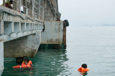 Tioman, Malezya - 20 Nisan 2022: İnşaat işçisi beton bir iskeleyi onarmak için deniz suyunun üzerinde yapı iskelesi kuruyor.