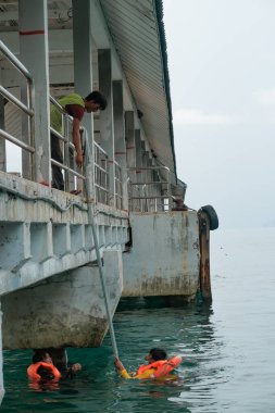 Tioman, Malezya - 20 Nisan 2022: İnşaat işçisi beton bir iskeleyi onarmak için deniz suyunun üzerinde yapı iskelesi kuruyor.