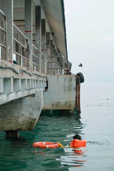 Tioman, Malezya - 20 Nisan 2022: İnşaat işçisi beton bir iskeleyi onarmak için deniz suyunun üzerinde yapı iskelesi kuruyor.