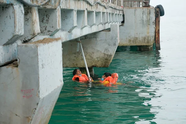 Tioman, Malezya - 20 Nisan 2022: İnşaat işçisi beton bir iskeleyi onarmak için deniz suyunun üzerinde yapı iskelesi kuruyor.