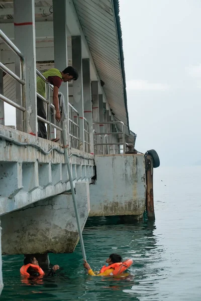 Tioman, Malezya - 20 Nisan 2022: İnşaat işçisi beton bir iskeleyi onarmak için deniz suyunun üzerinde yapı iskelesi kuruyor.