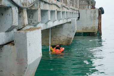 Tioman, Malezya - 20 Nisan 2022: İnşaat işçisi beton bir iskeleyi onarmak için deniz suyunun üzerinde yapı iskelesi kuruyor.