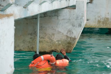 Tioman, Malezya - 20 Nisan 2022: İnşaat işçisi beton bir iskeleyi onarmak için deniz suyunun üzerinde yapı iskelesi kuruyor.