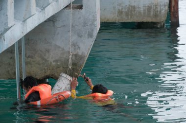 Tioman, Malezya - 20 Nisan 2022: İnşaat işçisi beton bir iskeleyi onarmak için deniz suyunun üzerinde yapı iskelesi kuruyor.